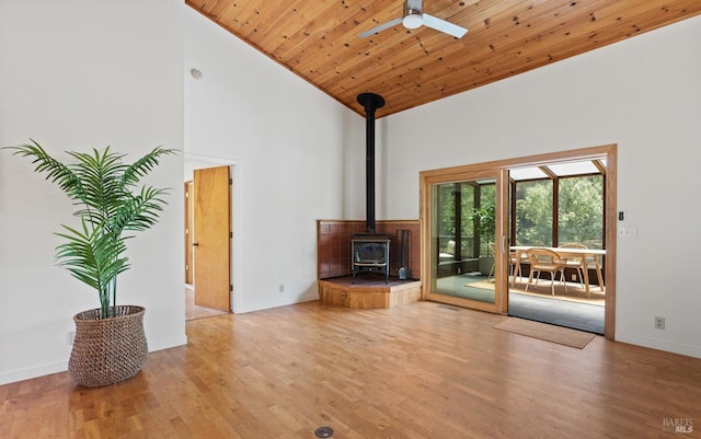 unfurnished living room featuring wood finished floors, high vaulted ceiling, a wood stove, ceiling fan, and wooden ceiling