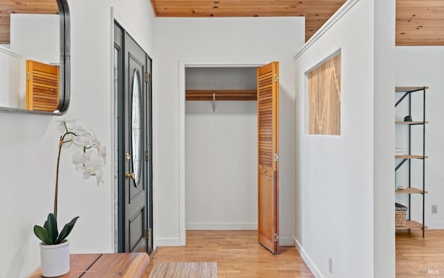 interior space featuring light wood-style flooring, wood ceiling, and baseboards