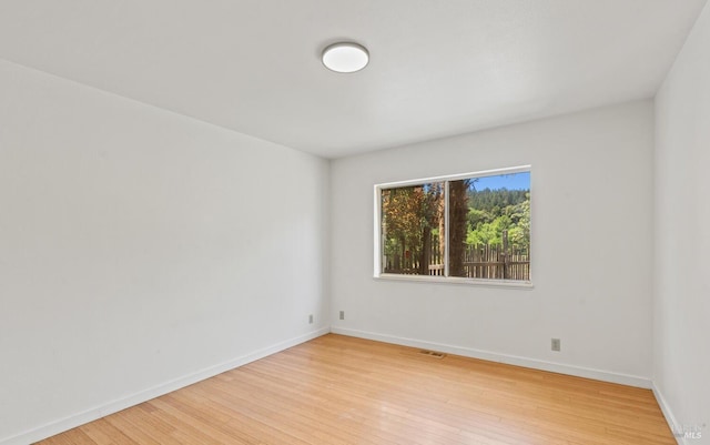 unfurnished room with visible vents, light wood-style flooring, and baseboards