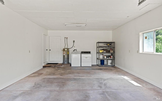 garage with baseboards, electric water heater, and independent washer and dryer