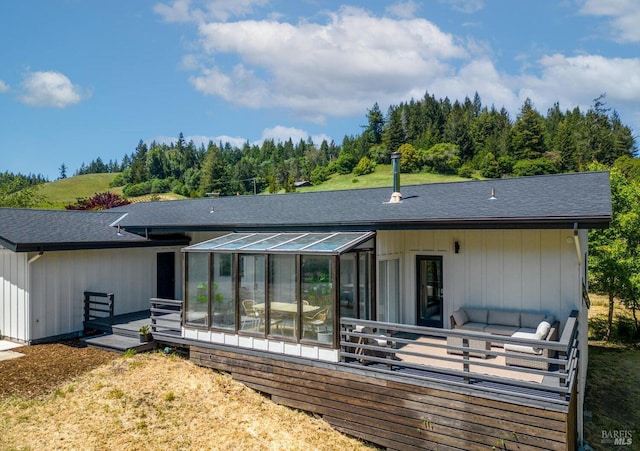 rear view of property with a shingled roof and a sunroom