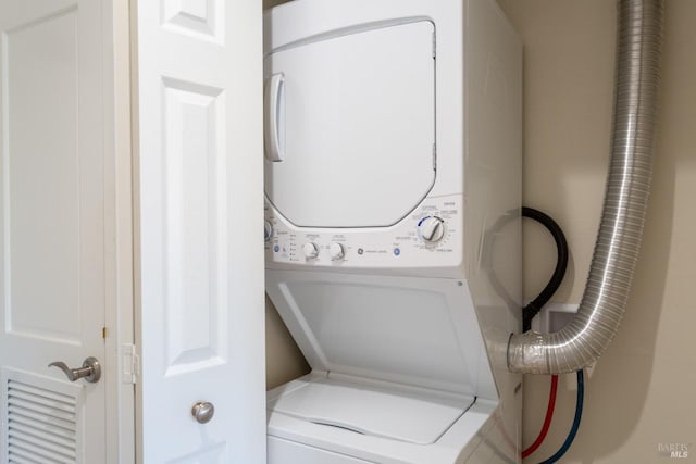 clothes washing area with stacked washing maching and dryer