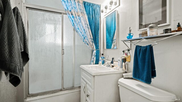 full bathroom featuring combined bath / shower with glass door, vanity, and toilet