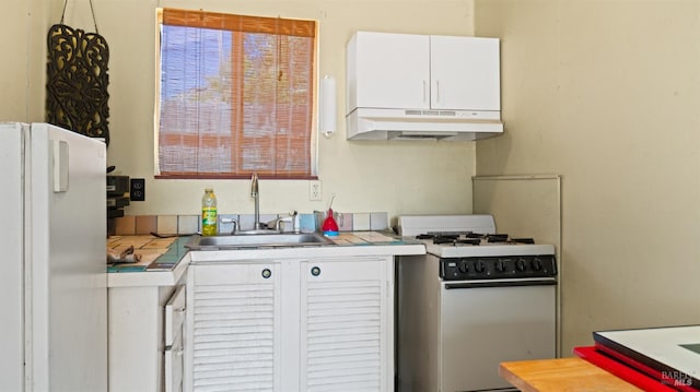 kitchen with white appliances, white cabinetry, sink, and tile counters