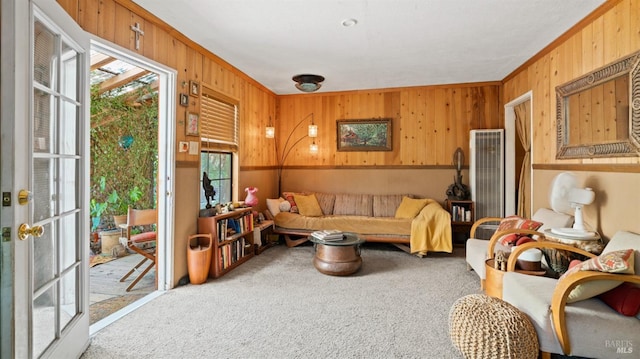 living room with wooden walls, light colored carpet, and crown molding