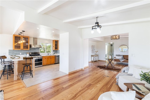 living room with beam ceiling, light hardwood / wood-style floors, sink, and ceiling fan with notable chandelier