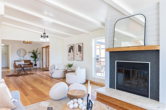 living room with beam ceiling, a tile fireplace, and wood-type flooring