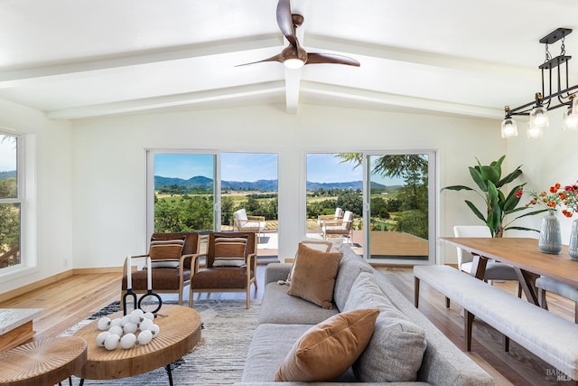 sunroom / solarium featuring a mountain view, lofted ceiling with beams, and ceiling fan