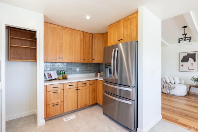 kitchen with pendant lighting, decorative backsplash, stainless steel refrigerator with ice dispenser, and light hardwood / wood-style flooring