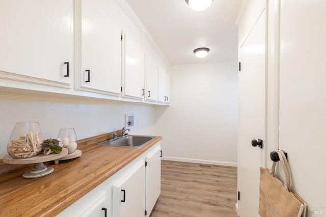 laundry area with cabinets, light wood-type flooring, sink, and hookup for a washing machine