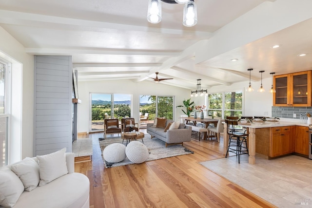 living room with a chandelier, light hardwood / wood-style flooring, beamed ceiling, and sink