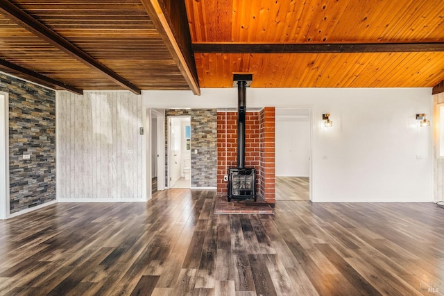 unfurnished living room with beamed ceiling, wood ceiling, brick wall, a wood stove, and dark hardwood / wood-style floors