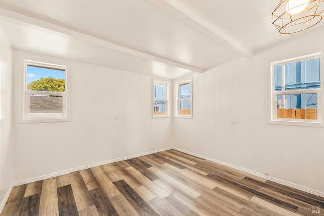 spare room with hardwood / wood-style flooring and beamed ceiling