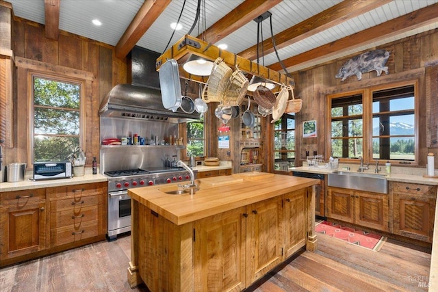 kitchen featuring sink, butcher block countertops, wooden walls, and light wood-type flooring