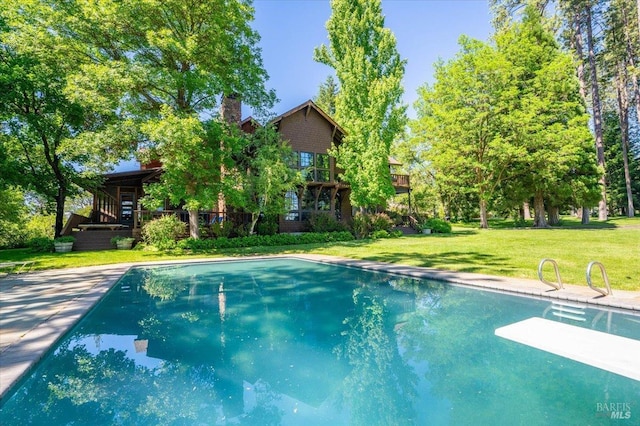 view of swimming pool featuring a lawn and a diving board