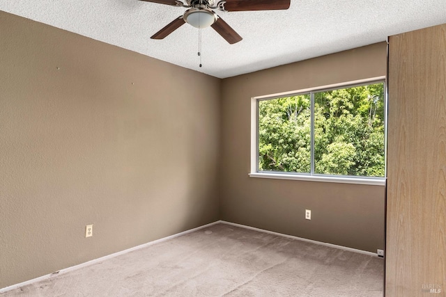 spare room with ceiling fan, light colored carpet, and a textured ceiling