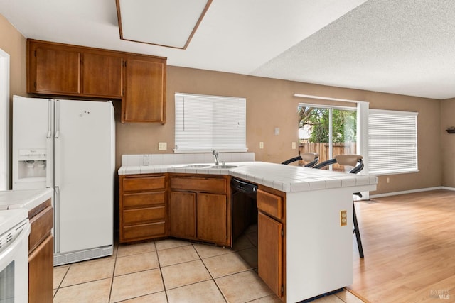 kitchen featuring sink, tile counters, white appliances, kitchen peninsula, and a textured ceiling