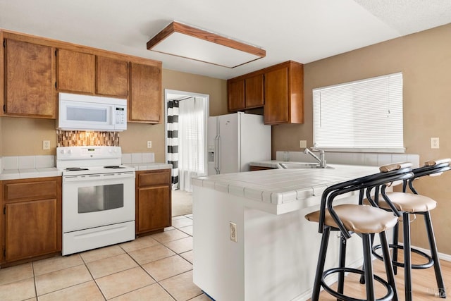 kitchen featuring sink, white appliances, tile countertops, and a kitchen breakfast bar