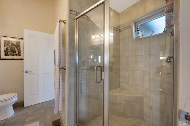 bathroom with tile patterned flooring, toilet, and a shower with shower door