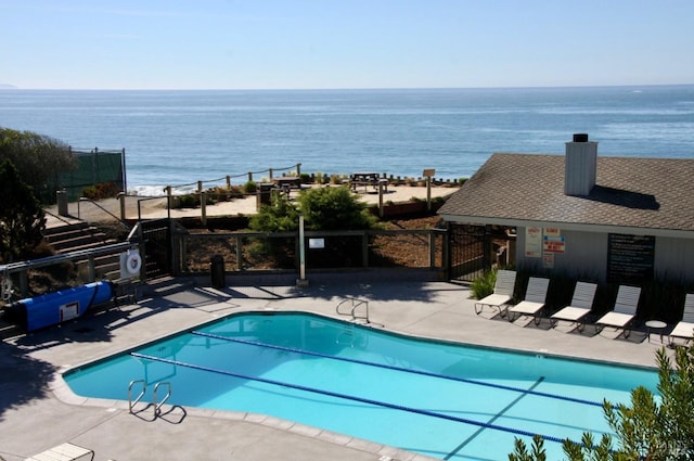 view of pool featuring a water view and a patio