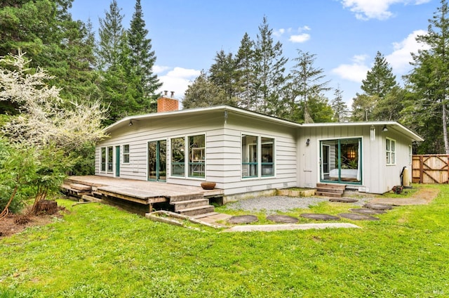 back of house with a wooden deck and a lawn