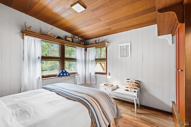 bedroom featuring light hardwood / wood-style flooring, wooden ceiling, multiple windows, and wooden walls