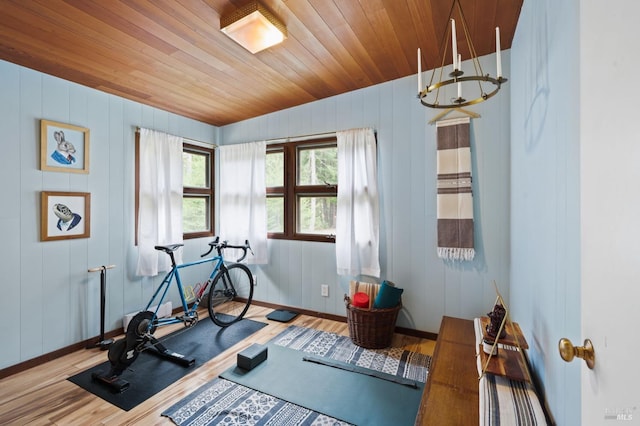 exercise room with wood ceiling, light hardwood / wood-style flooring, and a chandelier