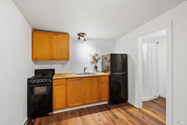 kitchen with black appliances, sink, and hardwood / wood-style flooring