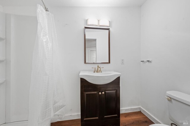 bathroom featuring walk in shower, toilet, hardwood / wood-style flooring, and vanity