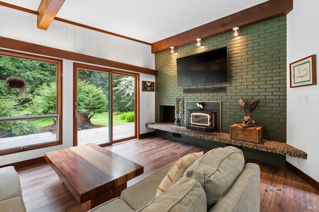 living room featuring dark wood-type flooring, a brick fireplace, and beam ceiling