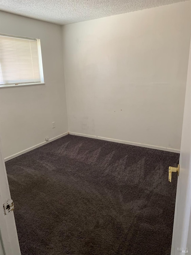 carpeted empty room with a textured ceiling