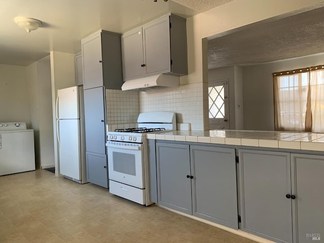 kitchen featuring washer / dryer, tile counters, a textured ceiling, and white appliances