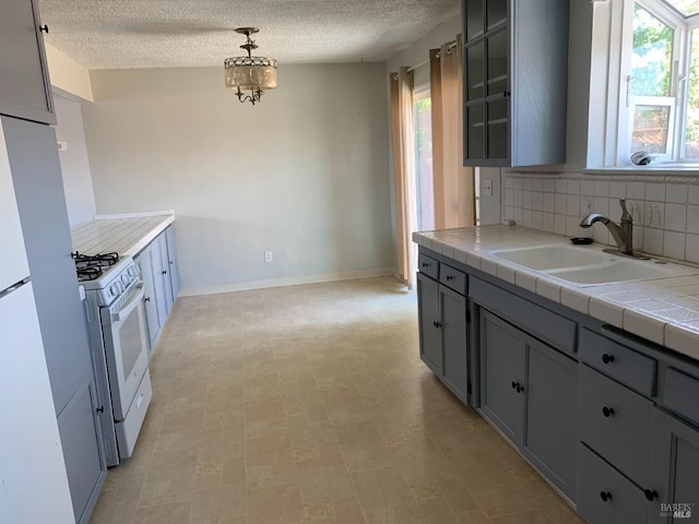 kitchen featuring sink, white appliances, a healthy amount of sunlight, decorative light fixtures, and tile countertops