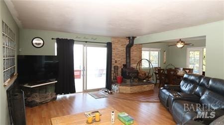 living room featuring hardwood / wood-style floors, ceiling fan, and a wood stove