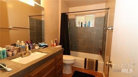 full bathroom with toilet, shower / tub combo with curtain, and large vanity