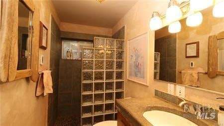 bathroom featuring tile walls, toilet, and oversized vanity