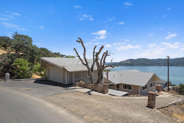 ranch-style house with a garage, a water view, and driveway