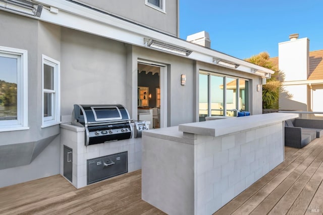 view of patio / terrace with a wooden deck, a bar, and grilling area