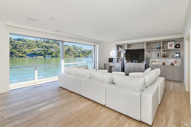 living room featuring light hardwood / wood-style flooring, crown molding, and a water view