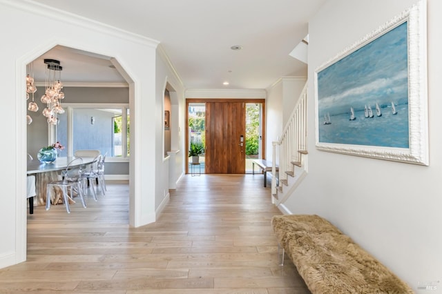 entryway with ornamental molding, light hardwood / wood-style floors, and a notable chandelier