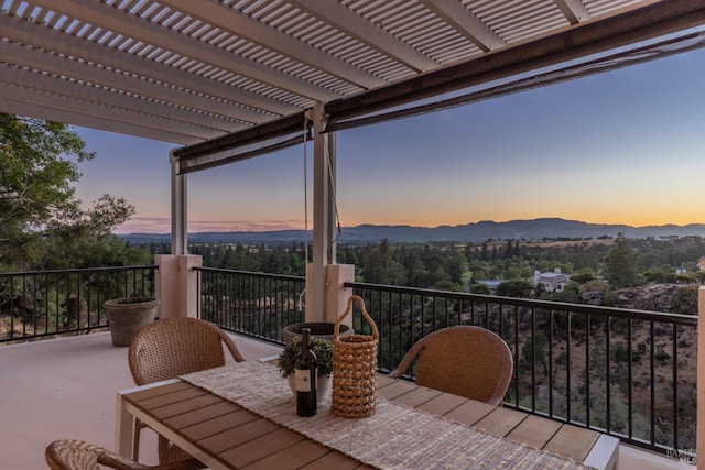 balcony at dusk with a mountain view and a pergola