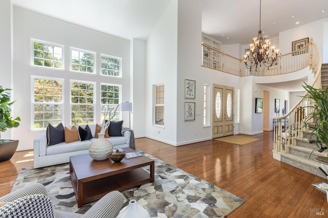 living room featuring hardwood / wood-style flooring, a towering ceiling, and an inviting chandelier