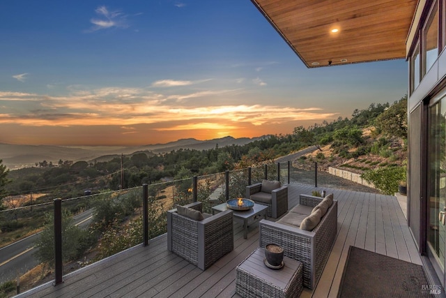 deck at dusk featuring a mountain view and an outdoor living space with a fire pit