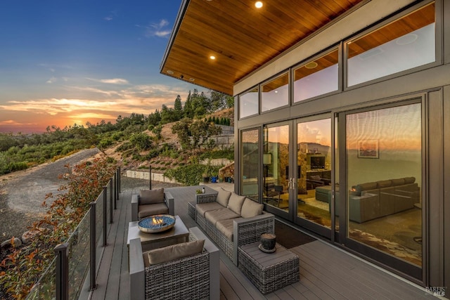 balcony at dusk featuring an outdoor living space with a fire pit and french doors