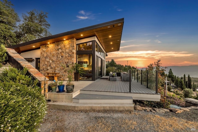 back house at dusk with a wooden deck