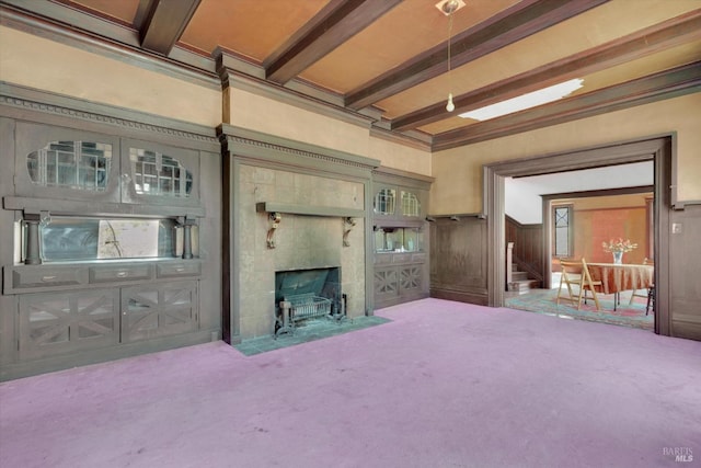 carpeted living room featuring beam ceiling and a tiled fireplace