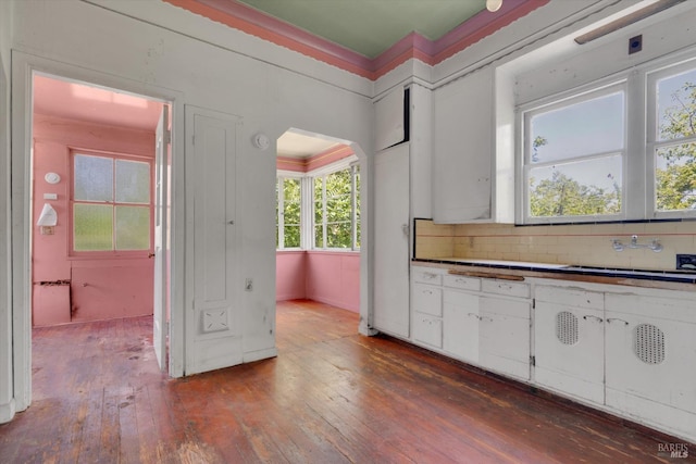 kitchen featuring sink, white cabinetry, wood-type flooring, and backsplash