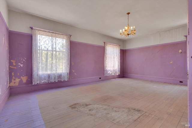 unfurnished room featuring plenty of natural light, a chandelier, and wood-type flooring