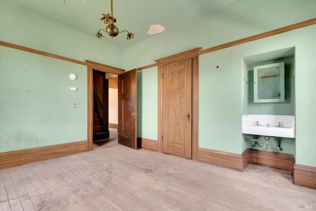 unfurnished bedroom featuring hardwood / wood-style floors, sink, and a chandelier