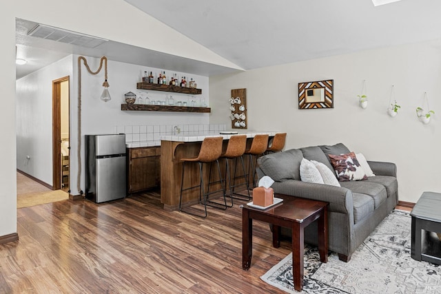 living room featuring indoor bar, dark hardwood / wood-style flooring, and lofted ceiling